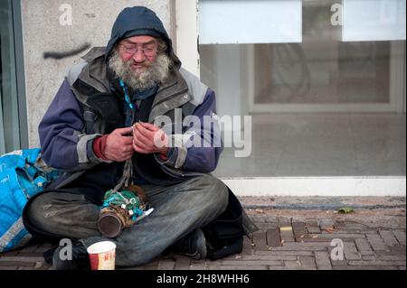 Den Haag, Niederlande. Lange Zeit sitzen Obdachlose Alkoholiker in den Straßen von Down Town Den Haag aufgrund von Armut und Mangel an öffentlicher, psychischer Gesundheitsversorgung. Stockfoto