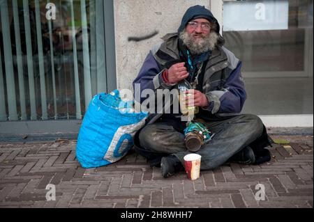 Den Haag, Niederlande. Lange Zeit sitzen Obdachlose Alkoholiker in den Straßen von Down Town Den Haag aufgrund von Armut und Mangel an öffentlicher, psychischer Gesundheitsversorgung. Stockfoto