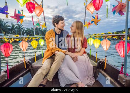 Ein glückliches Paar von Reisenden fährt auf einem Nationalboot auf dem Hintergrund der alten Stadt Hoi in Vietnam. Vietnam öffnet sich nach der Quarantäne wieder für Touristen Stockfoto