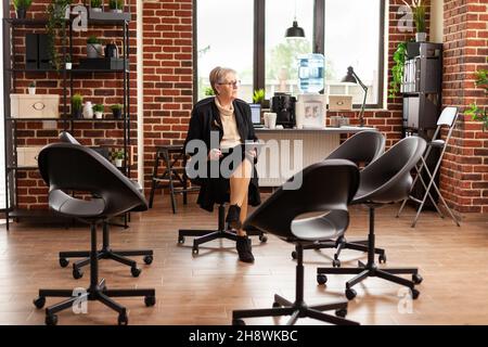 Mental Specialist schaut sich um und wartet darauf, dass ein Meeting beginnt. Frauentherapeutin mit Clipboard denkt an Gruppentherapie Sitzung, um Anleitung und Unterstützung für Menschen zu geben. Stockfoto