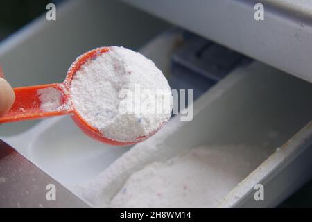 Gießen von Waschpulver in Kunststoffschale der Waschmaschine Stockfoto