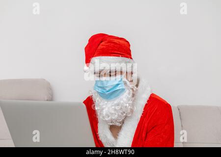Mann als Weihnachtsmann mit Laptop gekleidet Stockfoto