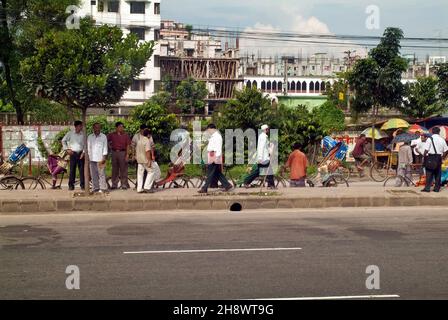 Dhaka, Bangladesch - 17. September 2007: Nicht identifizierte Personen an einer Bushaltestelle und andere mit Rikschas Stockfoto