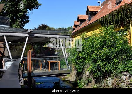 Stainz, Österreich - 23. September 2021: Café-Restaurant mit Sitzecke über dem Fluss Stockfoto