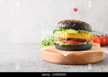Veganer Burger auf pflanzlicher Basis mit Gemüsefleischbällchen und schwarzen Kohlebuns auf grauem Hintergrund, mit Liebe hergestellt. Nahaufnahme. Gesundes Essen und Abendessen für VA Stockfoto