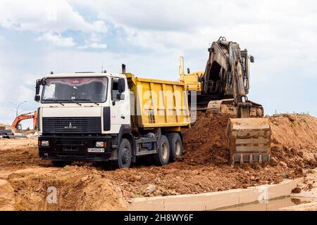 MINSK, WEISSRUSSLAND - 2. Juli 2021: Schwerer Industriebagger in hellgelb, der auf der Baustelle in der Stadt arbeitet. Stockfoto