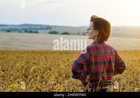 Kaukasische Farmarbeiterin inspiziert Soja am Sommerabend irgendwo in der Ukraine Stockfoto