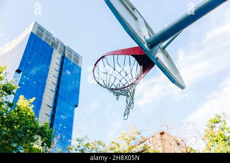 Von unten von Basketballkorb mit Netz hängen auf Sportplatz im Park an sonnigen Tag Stockfoto