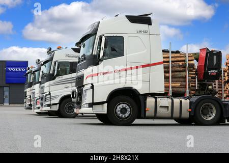 Vier weiße Volvo FH-Schwerlastwagen, die im Sommer auf Asphalt geparkt wurden, Volvo Truck Center-Logo auf dem Hintergrund. Forssa, Finnland. 25. Juni 2016. Stockfoto