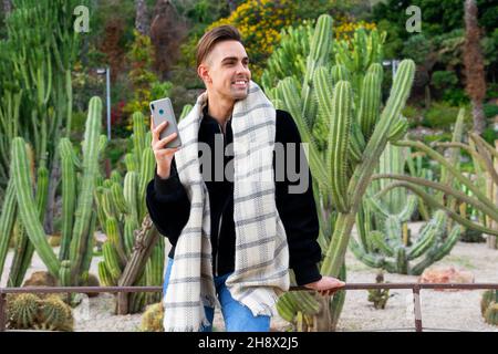 Ganzer Körper von jungen ethnischen schlanken Weibchen mit langen dunklen Haaren tragen schwarzen Bodysuit und spitzenschuhe sitzen auf dem Dach mit gekreuzten Beinen Stockfoto