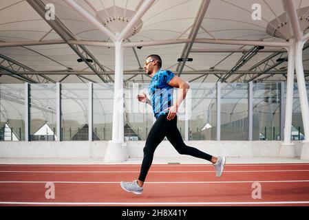Sportlicher Mann mit Sportbekleidung und Sonnenbrille läuft auf der Laufstrecke Stockfoto