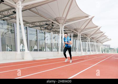 Sportlicher Mann mit Sportbekleidung und Sonnenbrille läuft auf der Laufstrecke Stockfoto