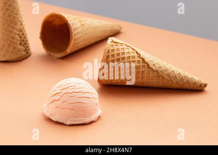 Rosafarbene Eislöffel und Waffelkegel auf dem Tisch im Studio Stockfoto