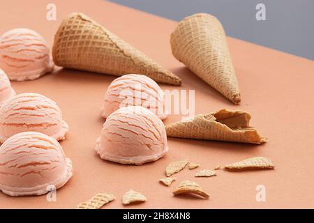 Rosafarbene Eislöffel und Waffelkegel auf dem Tisch im Studio Stockfoto