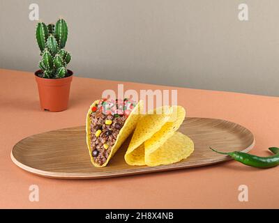 Hackfleischtacos mit Mais und Sauce auf Holzplatte zerkleinern Stockfoto