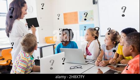 Digitale Zusammenstellung von Fragezeichen über Lehrer, die den Schülern im Klassenzimmer einen Tablet-pc zeigen Stockfoto