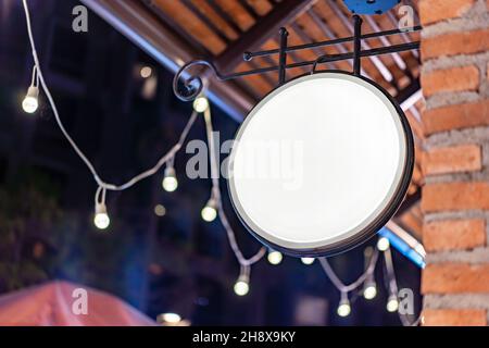 Der Circle White Lightbox hat an der Wand vor dem Backsteinpfosten in einem Tungsten Ambient Umgebung Vintage Shopping Community Mall gehängt. Stockfoto