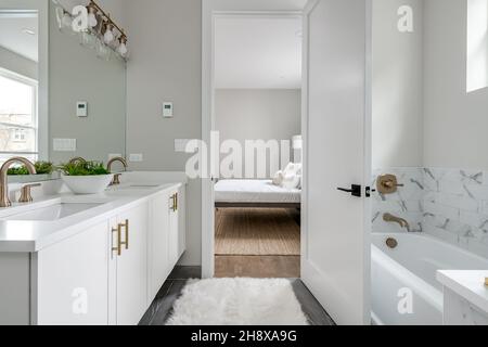 Modernes weißes Badezimmer mit Badewanne und goldenen Armaturen Blick auf das Minimal Bedroom Stockfoto