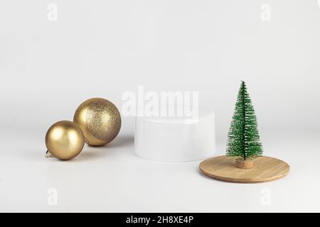 Leere runde weiße und hölzerne Podium. Minimale Weihnachtsszene mit Podium, Weihnachtskugeln und einem kleinen Weihnachtsbaum auf weißem Hintergrund. Neujahr CO Stockfoto