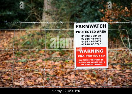 Farmwatch-Schild mit geschütztem Bereich auf einem Zaun um Norfolk Woodland. Stockfoto