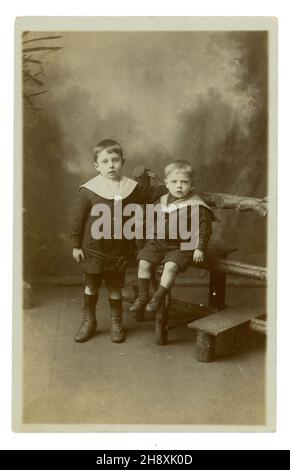 Original Edwardianische Studioportrait-Postkarte mit Requisiten und gemaltem Hintergrund, von zwei Brüdern namens Willie und Harry, Illingworth, Yorkshire, England, UK um 1910 Stockfoto