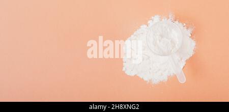 Draufsicht Proteinpulverhaufen mit Messlöffel auf hellbraunem Hintergrund Stockfoto