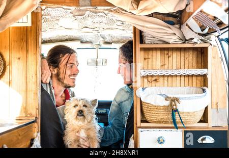 Indie-Paar mit kleinem Hund, der zusammen mit Oldtimer-Kleintransporter unterwegs ist - Reise-Lifestyle-Konzept mit Hipster-Menschen auf Minivan-Abenteuer Stockfoto