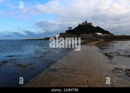 St. Michael's Mount, eine Gezeiteninsel in Mount's Bay, und angebauter, künstlich angeschlossener Damm, der bei Dämmerung teilweise bedeckt ist (Cornwall, Großbritannien). Stockfoto