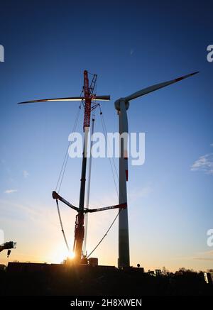 02. Dezember 2021, Schleswig-Holstein, Brunsbüttel: Das dritte Rotorblatt wird mit einem mobilen Kran auf einer Enercon-Windkraftanlage (E150) in einem Windpark zwischen Marne und Brunsbüttel montiert. Laut einer Studie könnten sich die Einsparungen von CO2 bis 2030 im Vergleich zu den bisherigen Plänen der Großen Koalition aufgrund der Wind- und Solarstrompläne der Ampelkoalition mehr als verdoppeln. Foto: Christian Charisius/dpa Stockfoto