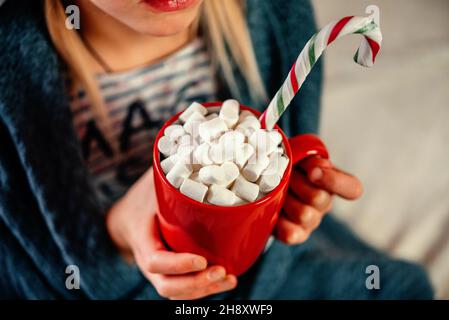 Hände halten eine rote Tasse heiße Schokolade mit Marshallows Weihnachten Hintergrund Stockfoto