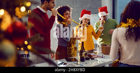 Neujahr und Weihnachtsfeier. Eine kleine Gruppe multikultureller Freunde, die im Büro stehen und sich am Silvesterabend gut Vergnügen. Stockfoto