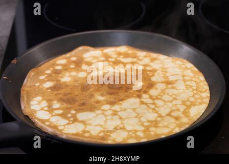 Pfannkuchen in einer Pfanne. Kochen Sie die Zubereitung hausgemachter Pfannkuchen Stockfoto