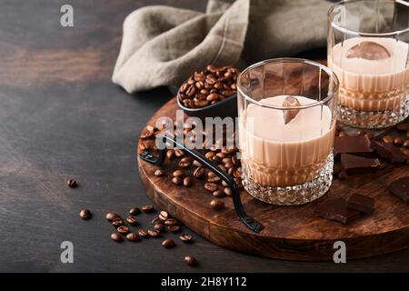 Glas irischer Rahm-Baileys-Likör mit gerösteten Kaffeebohnen, Zimt und Schokolade auf dunklem Holz-Hintergrundtisch. Selektiver Fokus. Stockfoto