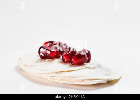 Leuchtend rote Granatapfelkerne auf weißer Muschel Stockfoto