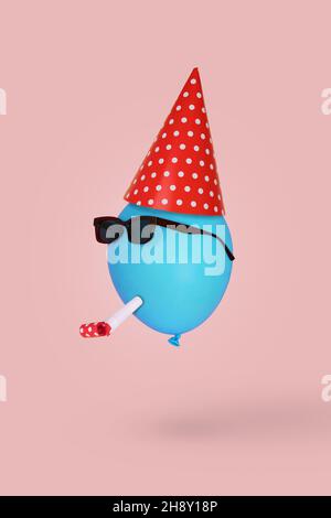 Blauer Ballon in Sonnenbrille mit Geburtstagshut und Pfeife schwebt in der Luft vor rosa Hintergrund. Minimal Kreativität und Glück Konzept . Fun P Stockfoto