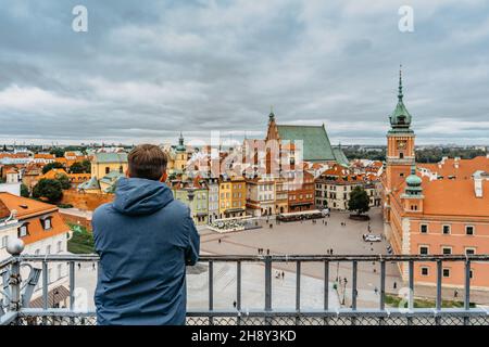 Mann Reisende genießen Blick auf das Königsschloss, Schlossplatz und Altstadt, Warschau, Polen. Tourist Blick auf die historische Innenstadt. Stadt Anorama auf Wolke Stockfoto