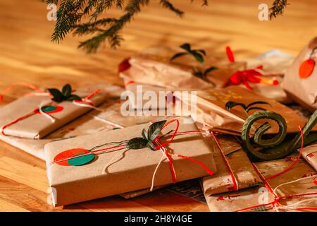 Weihnachten Zusammensetzung.Weihnachten Geschenke mit roten grünen Bändern und Baum Zweig Dekor.Geschenke verpackt in Handwerk recyceltes Papier und Seil Bogen.Winterurlaub Stockfoto