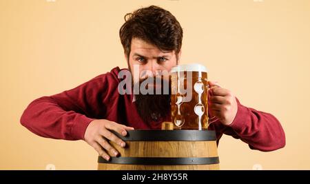 Ernsthafter bärtiger Mann mit Bier. Gutaussehender Rüde schmeckt frisch gebrautes Bier aus dem Becher. Alkohol Trinken. Stockfoto