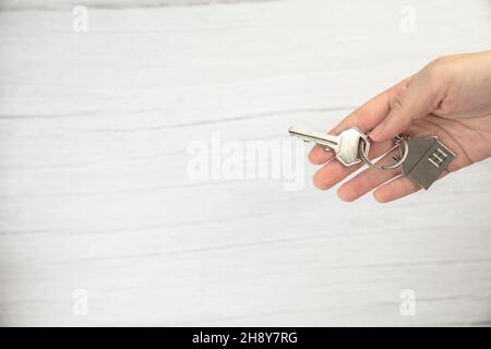 makler weibliche Hand hält neue Tür Schlüssel zum neuen Haus auf weißem Hintergrund Draufsicht mit Kopieplatz, Kauf neuer Haus Konzept Stockfoto