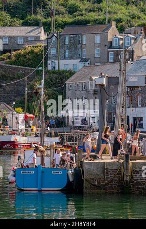 Touristen / Urlauber steigen von einem Ausflugsboot aus, das gerade in Mevagissey Harbour - Mevagissey, Cornwall, Großbritannien, angedockt ist. Stockfoto