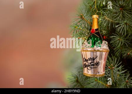 Weihnachtliche Verzierung Champagnerflasche in einem Eimer Eis, der an einem Tannenbaum hängt. Speicherplatz kopieren. Stockfoto