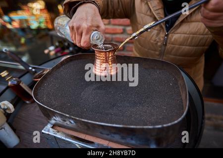 Aromatischer Kaffee, der in heißem Sand gebrüht wird türkischer Kaffee, der in Cezve braut Stockfoto