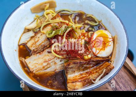 Schüssel Miso Pork Ramyun mit Schwein- und Hühnerbrühe, geraden Nudeln, Schweinebauch, gebratenen Pilzen, Süßkartoffeln, kale, Kimchi, Knoblauchöl, Nitamago Stockfoto