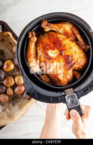 Ein ganzes Huhn in einem Luftkühlerkonzept gekocht. Eine gesunde, nahrhafte hausgemachte Alternative zu frittiertem, im Laden gekauftem Fleisch. Serviert in der Fritteuse Stockfoto