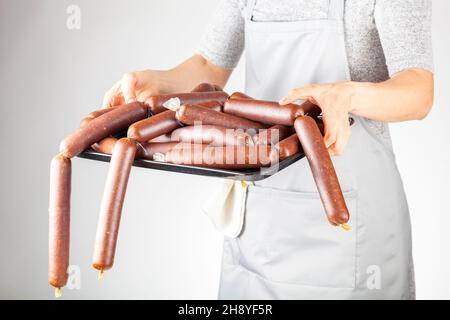 Eine Küchenchefin zeigt einen Haufen hausgemachter türkischer Sucuk oder Wurst auf einem Tablett. Fermentiertes, würziges rotes Fleisch-Konsumkonzept. Stockfoto