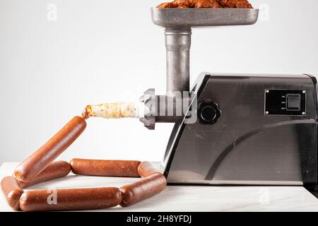 Nahaufnahme eines isolierten Bildes von hausgemachtem Sucuk oder Wurst, die mit einem elektrischen Stopfergerät in den Mantel gestopft wird. Stockfoto