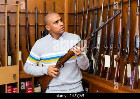 Porträt eines selbstbewussten Mannes in der Waffenhandlung mit Gewehr Stockfoto