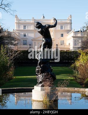 Blick auf die St John's Lodge, Regent's Park, London, Großbritannien, fotografiert an einem klaren Wintertag vom Rosengarten aus. Statue von Hylas im Vordergrund. Stockfoto