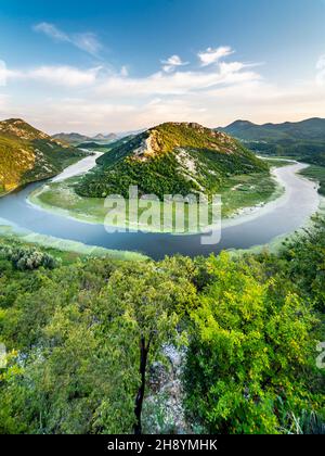 Blick vom Aussichtspunkt Pavlova Strana auf ein kleines Boot, das die Hufeisenkurve umrundet, und die albanischen Berge in der Ferne. Stockfoto