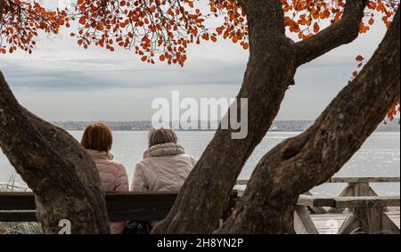 Zwei Senioren saßen auf einer Bank. Ältere Frauen freunds in einem herbstlichen Park am Fluss. Stockfoto